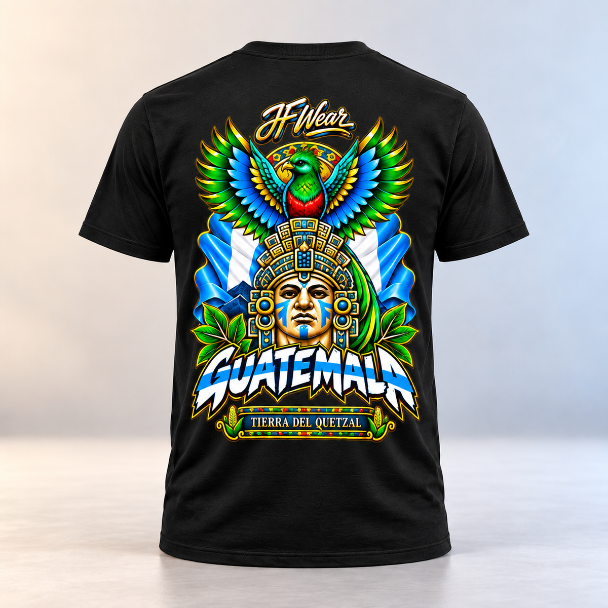 A black short-sleeve t-shirt shown from the back, featuring a large, colorful graphic print with a Guatemalan theme. The design includes a parrot, a Mayan face, the word 'GUATEMALA' in bold white letters with blue shadows, the text 'J.