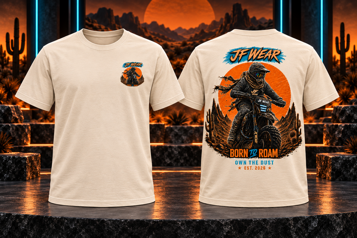 Two views of a cream-colored graphic t-shirt displayed on a dark stage with a desert sunset backdrop. The front view shows a small chest graphic, and the back view features a large motocross graphic with the text 'JF WEAR' and 'BORN TO ROAM'.