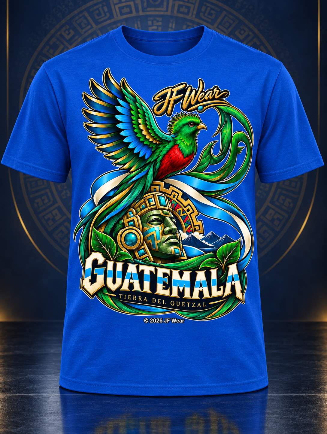 A royal blue short-sleeve t-shirt featuring a large, colorful graphic print of a green and red quetzal bird, a Mayan head, and the text 'If Wear GUATEMALA' and 'TIERRA DEL QUINTAL'.