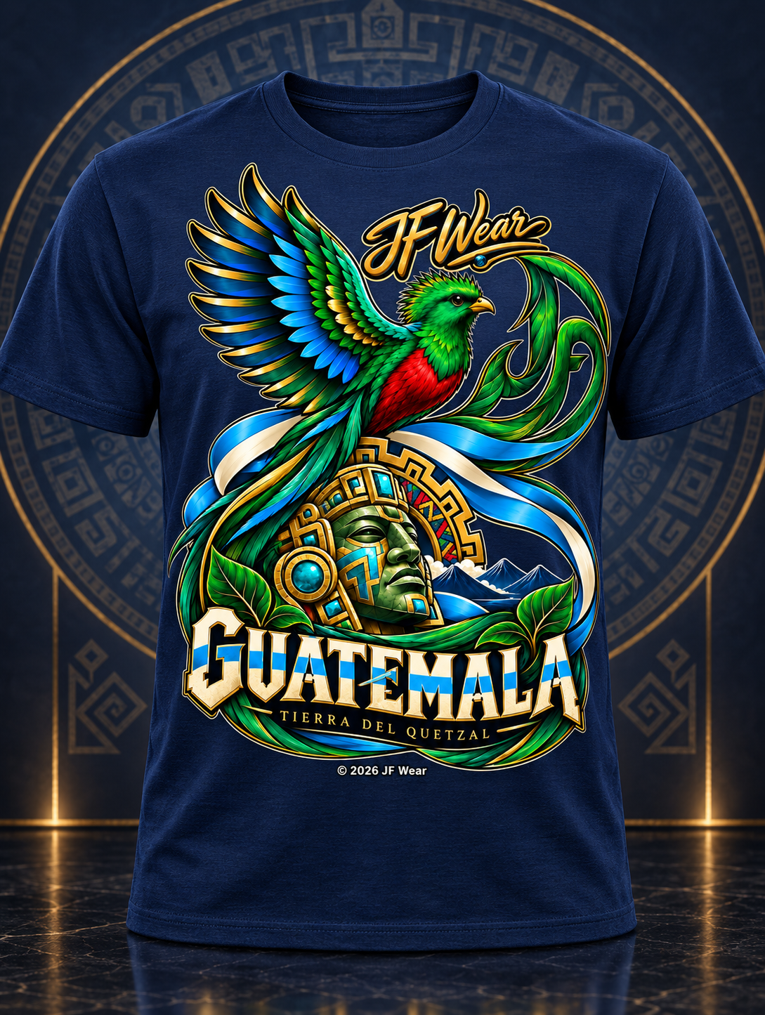A navy blue short-sleeve t-shirt with a large, colorful graphic print on the front. The design features a vibrant green and red bird perched on a golden headdress, with the text 'JF Wear' above and 'GUATEMALA TIERRA DEL QUetzAL' below.
