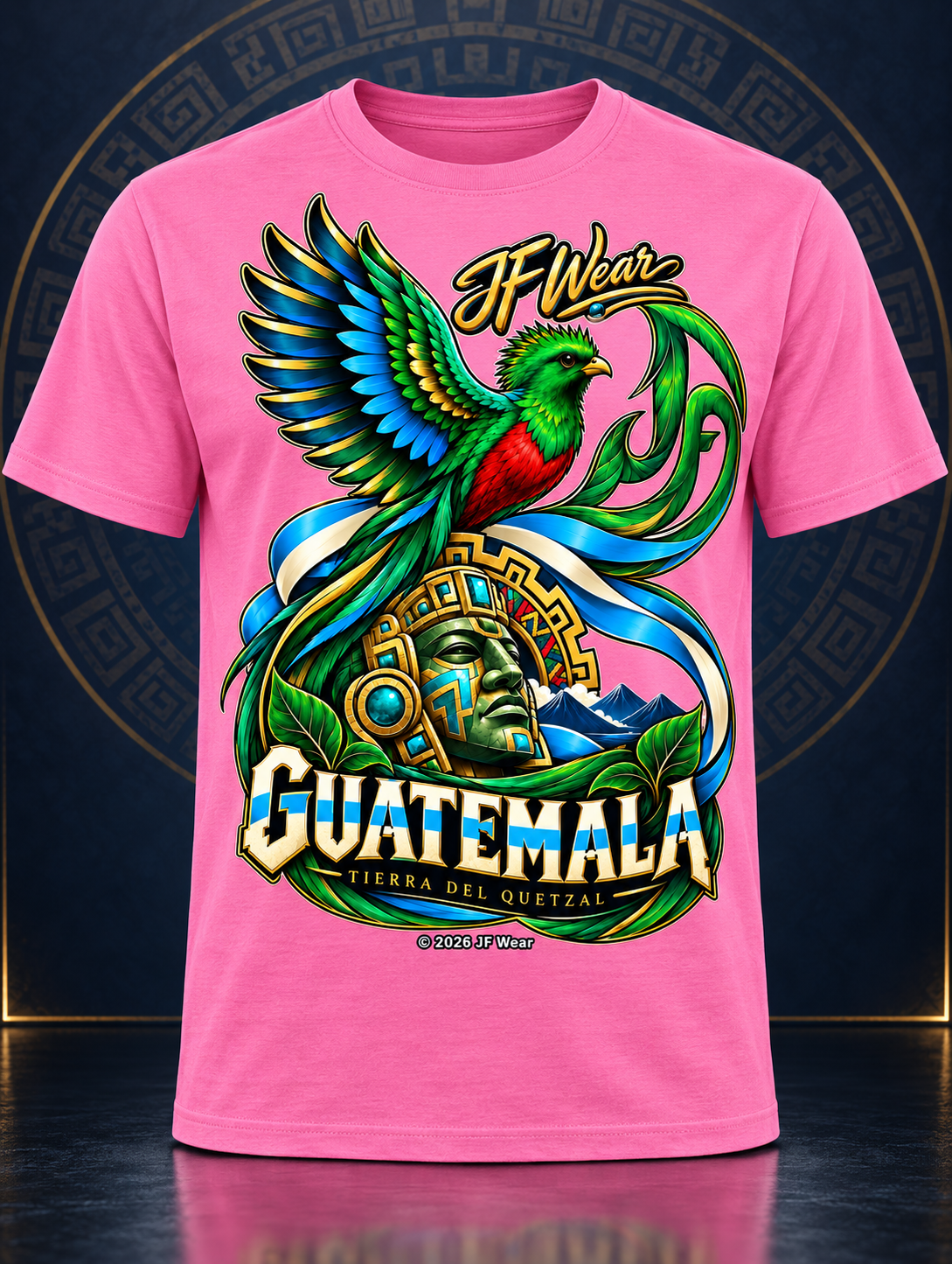 A bright pink short-sleeve t-shirt featuring a large, colorful graphic print on the front. The graphic depicts a green and blue bird perched on a golden Aztec-style head with the text 'If Wear GUATEMALA' and 'TIERRA DEL ORIENTAL' in stylized lettering.