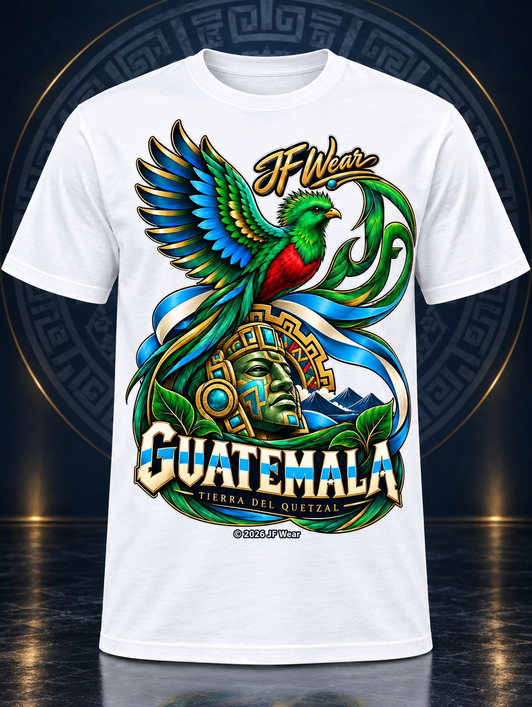 A white short-sleeve t-shirt with a large, colorful graphic print featuring a green and red quetzal bird, a green stone head, and the text 'H Wear GUATEMALA TIERRA DEL OUESTAL' on a dark, decorative background.
